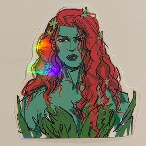 Op de afbeelding: Een holografische sticker met een cartoonillustratie van Poison Ivy, een superschurk van DC Comics. Ze heeft rood haar, groene huid en is omringd door groene bladeren.