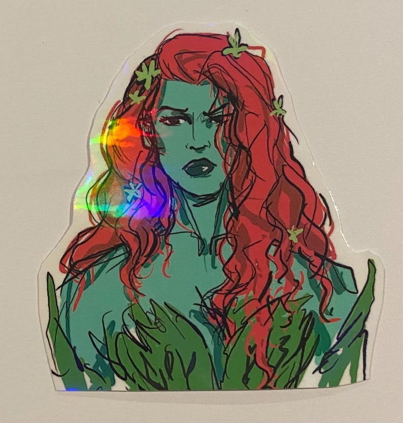 Op de afbeelding: Een holografische sticker met een cartoonillustratie van Poison Ivy, een superschurk van DC Comics. Ze heeft rood haar, groene huid en is omringd door groene bladeren.