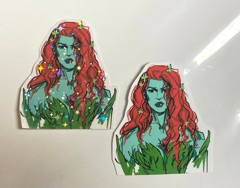 Op de afbeelding: Twee stickers met een vrouw met groene huid, rood haar en groene wijnstokken. De vrouw heeft een strenge uitdrukking en draagt een groene, bladerrijke outfit. De sticker links heeft een holografische afwerking.