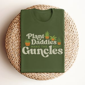 May include: Green t-shirt with the text "Plant Daddies Make the Best Guncles" in a retro font. The text is surrounded by illustrations of potted plants.
