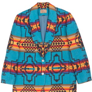 May include: A long-sleeve blazer featuring a vibrant geometric pattern in shades of turquoise, orange, red, yellow, and black. The garment has a shawl collar, two silver-toned buttons at the front closure, and two horizontal slit pockets.