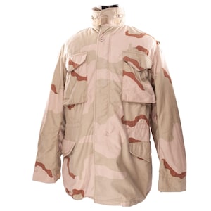 May include: A tan and brown camouflage military jacket with multiple pockets and a high collar. The jacket has a button-up front and a desert camouflage pattern. The jacket is made of a durable material.