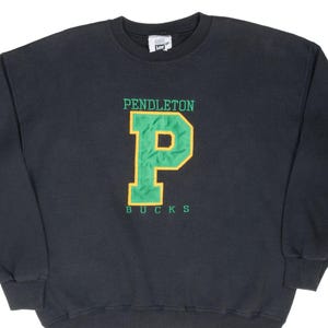 May include: A dark gray sweatshirt with the word "PENDLETON" above a large green letter "P" with a gold outline. Below the "P" is the word "BUCKS" in green. The sweatshirt has a crew neck and long sleeves.