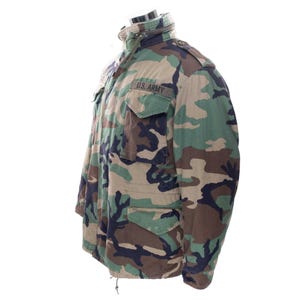 May include: Camouflage pattern jacket with the text "U.S. ARMY" on a patch. The jacket features a high collar, multiple pockets, and a drawstring at the bottom. The color scheme includes shades of green, brown, and black.