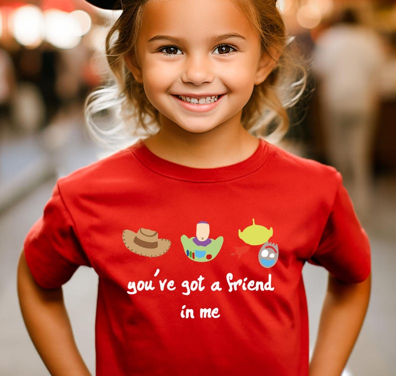 May include: Red short-sleeved t-shirt with a cartoon image of Woody, Buzz Lightyear, and Alien from Toy Story. The shirt has the text "you've got a friend in me" printed on it.