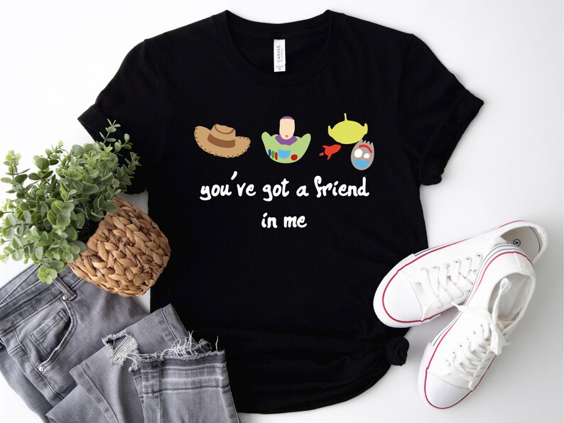 May include: Black t-shirt with a white graphic of the Toy Story characters Woody, Buzz Lightyear, and the aliens. The text "you've got a friend in me" is printed below the characters.