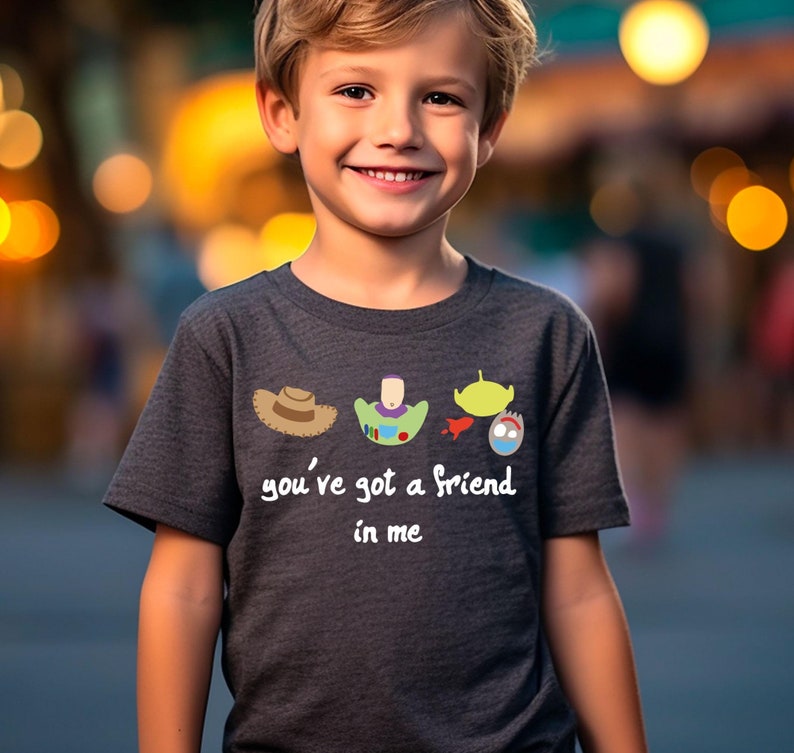 May include: A dark grey t-shirt with a graphic of the Toy Story characters Woody, Buzz Lightyear, and Alien. The text "you've got a friend in me" is printed below the graphic.