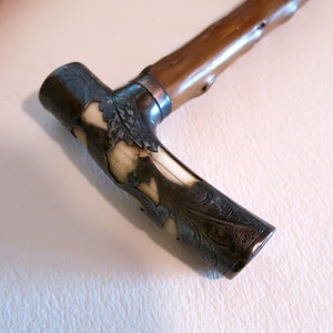 May include: A wooden walking stick with a silver and ivory handle. The handle is intricately carved with a floral design.