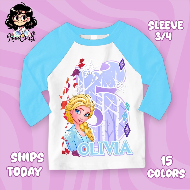 Puede incluir: Camiseta blanca y azul claro con mangas ragl&aacute;n con un gr&aacute;fico de Elsa de Frozen. El dise&ntilde;o incluye el nombre "Olivia" y el n&uacute;mero "5" con un fondo de bosque invernal. La camiseta tiene mangas 3/4.