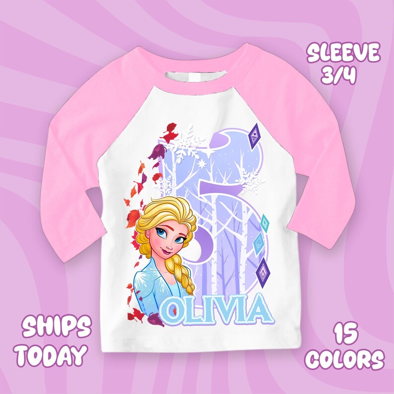Puede incluir: Una camiseta de manga ragl&aacute;n blanca y rosa con una imagen de dibujos animados de Elsa de Frozen. La camiseta tiene un gran n&uacute;mero 5 con un dise&ntilde;o de bosque invernal, el nombre "OLIVIA" y el texto "SLEEVE 3/4".