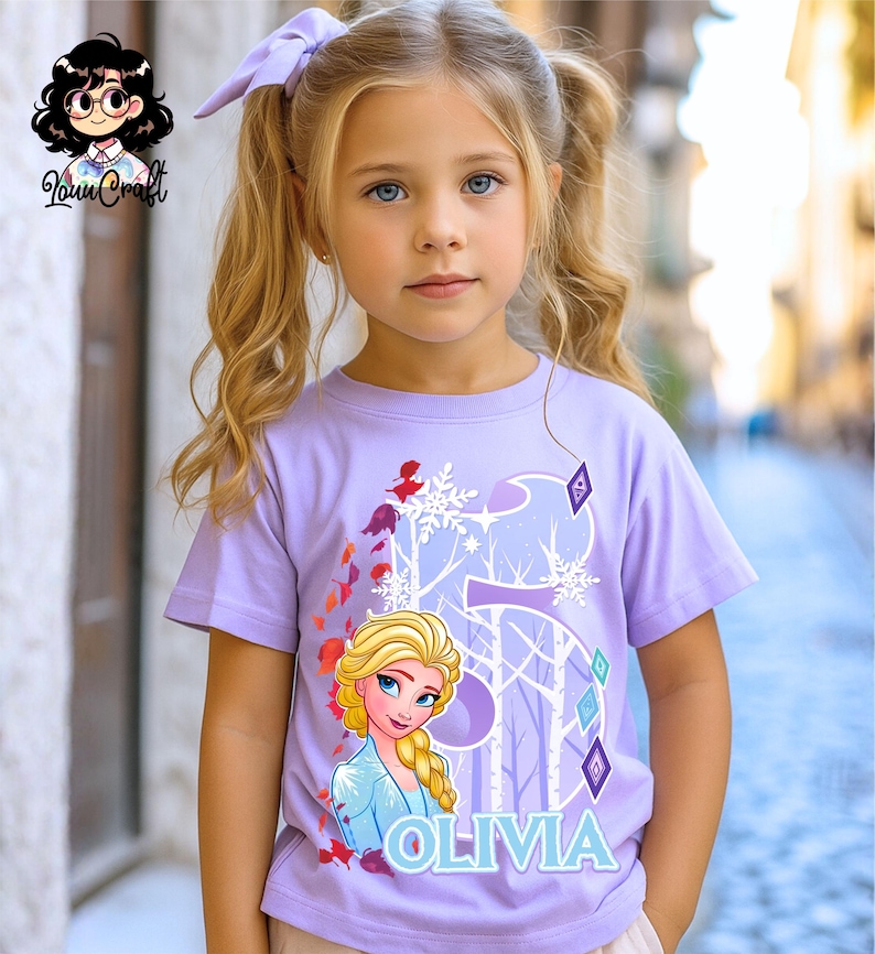 Puede incluir: Una camiseta lavanda con un gr&aacute;fico de Elsa de Frozen, el n&uacute;mero 5 y el nombre Olivia en azul. El dise&ntilde;o incluye copos de nieve y elementos forestales. La ni&ntilde;a lleva un lazo lavanda a juego.