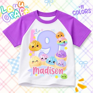 May include: A white t-shirt with purple raglan sleeves featuring a large light purple number nine, the name Madison in pink, and several colorful, smiling dumpling illustrations. The design includes small yellow stars and blue accents.