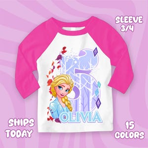 Puede incluir: Camiseta de manga ragl&aacute;n blanca y rosa con una imagen de dibujos animados de una mujer rubia con ojos azules. El n&uacute;mero 5 est&aacute; en el fondo con una escena de bosque. El nombre "OLIVIA" est&aacute; impreso en azul. La camiseta tiene mangas 3/4.