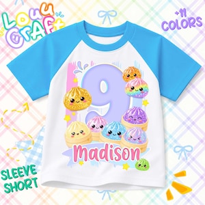 May include: A white t-shirt with bright blue raglan sleeves featuring a large purple number nine, the name Madison in pink, and several colorful, glittery, smiling dumpling characters in bamboo steamers printed on the front center.