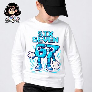 May include: White long-sleeve shirt with a blue pixelated graphic that reads "SIX SEVEN". The graphic features two cartoon characters in the shape of the numbers six and seven. The characters have blue bodies, white hands, and blue shoes.