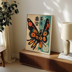 May include: A vintage-style poster featuring a colorful butterfly with black wings, orange and yellow accents, and large, round, red and blue eyes. The poster has Japanese text that reads "主 壽" and "萬壽無疆".