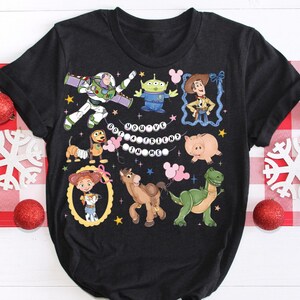 Puede incluir: Camiseta gris oscuro con personajes de dibujos animados coloridos de una popular pel&iacute;cula de animaci&oacute;n. La camiseta incluye a Buzz Lightyear, Woody y otros personajes, con la frase "You've Got a Friend in Me".