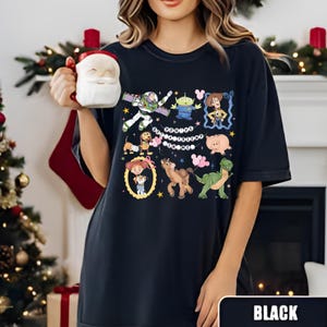 Puede incluir: Camiseta negra con gr&aacute;ficos de personajes de dibujos animados coloridos. El dise&ntilde;o incluye im&aacute;genes de un guardabosques espacial, un extraterrestre, una vaquera, un cerdo, un dinosaurio, un caballo y un perro. La palabra "BLACK" se muestra en la parte inferior de la imagen.