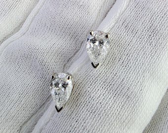Può includere: Un paio di orecchini a lobo a forma di pera con diamanti. I diamanti chiari e sfaccettati sono incastonati in una montatura in argento o oro bianco. Gli orecchini sono presentati su uno sfondo di tessuto bianco.