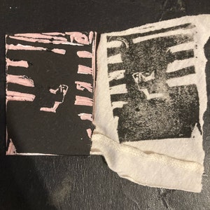 May include: A black and white print on fabric with pink stripes on a black background. The print is of a geometric design.