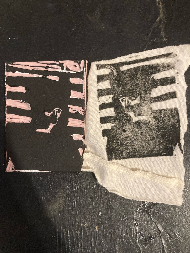 May include: A black and white print on fabric with pink stripes on a black background. The print is of a geometric design.