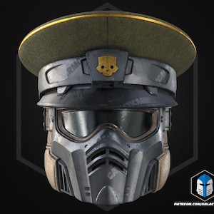 Op de afbeelding: Een futuristische militaire helm met een groene pet en een gouden rand. De helm heeft een schedel-embleem en een vizier. Het onderste deel van de helm is metaalgrijs met een beige kin. De tekst "GALACTIC ARMORY" is zichtbaar.