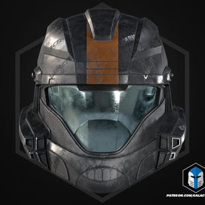 May include: A dark grey tactical helmet featuring a prominent vertical orange stripe running down the centre of the forehead. The helmet has a wide, reflective visor and angular, geometric plating with visible weathering and scuff marks.