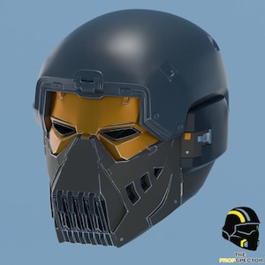 Op de afbeelding: Een donkerblauwe en antracietgrijze integraalhelm met een metallic goudkleurig vizier, hoekige geometrische panelen en een geventileerde kinbeschermer. In de rechterbenedenhoek staat een klein logo met de tekst THE PROPSPECTOR.