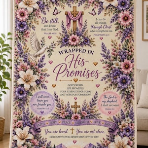 May include: A rectangular throw blanket featuring a cream background with a floral border of purple and pink flowers, lilies, and butterflies. It displays a central cross, a white dove, and religious text including "Wrapped in His Promises."