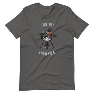 May include: A dark gray t-shirt with a cartoon witch wearing a colorful hat and the text "Resting Witch Face".