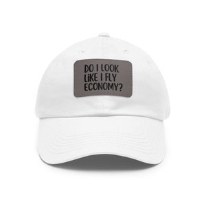 May include: White baseball cap with a gray patch that says "Do I look like I fly economy?"