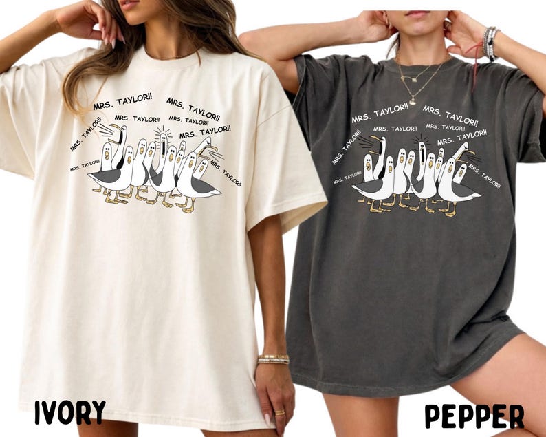 May include: Ivory and pepper-colored oversized t-shirts. Each shirt features a cartoon illustration of seagulls with the text "MRS. TAYLOR!!" repeated around them. The ivory shirt has "IVORY" printed at the bottom, and the pepper shirt has "PEPPER".