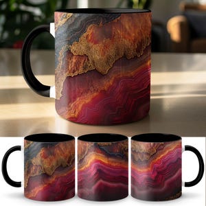 Könnte beinhalten: Eine Keramik-Kaffeetasse mit schwarzem Griff und Innenraum. Die Tasse zeigt ein lebendiges, abstraktes Design in Rot-, Gold- und Schwarztönen, das einem Geoden- oder Achatmuster ähnelt. Die Tasse wird auf einer hellen Oberfläche präsentiert.
