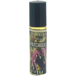 May include: A small glass bottle with a black cap and a label that says "Eromans Agathe Patchouli #114". The label has a floral design with pink and purple flowers.