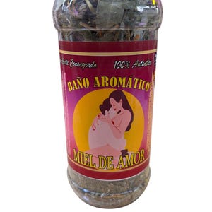May include: A clear glass jar filled with dried herbs and flowers. The label is red with yellow lettering and reads "Baño Aromático Miel de Amor" which translates to "Aromatic Bath Honey of Love".