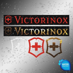 Puede incluir: La imagen presenta el logotipo de Victorinox en rojo y dorado, con el nombre de la marca arriba. El logotipo es un escudo con una cruz en su interior. También hay una insignia resistente al agua.