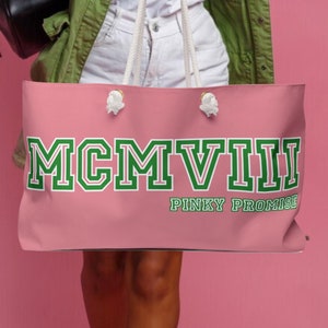 May include: Pink tote bag with white rope handles and the text "MCMVIII PINKY PROMISE" in green and white letters.