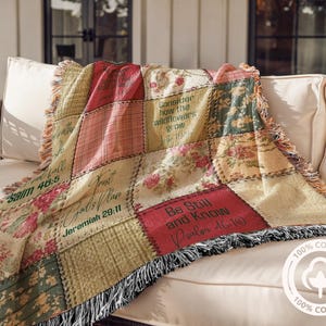 May include: A patchwork throw blanket with floral and plaid patterns in shades of red, green, and beige. The blanket features inspirational quotes and Bible verses. The throw is made of 100% cotton and has a fringed edge.