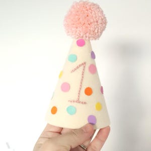 First Birthday Photo Prop Smash Cake Session Hat Baby Party Crown Colorful Celebration Accessory Handmade Felt Material Embroidered Number Design Fluffy Pom Decoration Cream Background Polka Dot Pattern Professional Photography Prop Trendy