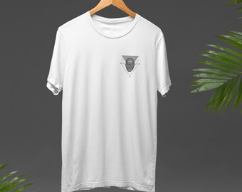 May include: White t-shirt with a geometric design featuring a stylized face with an eye in the center. The design is in gray and is located on the left chest of the shirt.
