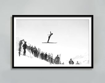 May include: A black and white photograph of a skier in mid-air, jumping off a ski ramp. The skier is wearing a ski suit and has their arms outstretched. There are other skiers standing on the ramp, watching the skier jump.