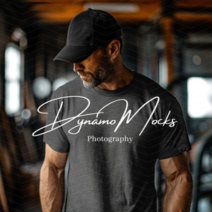 May include: A man wearing a black baseball cap and a dark gray t-shirt with the text "Dynamo Mocks Photography" printed on the front.