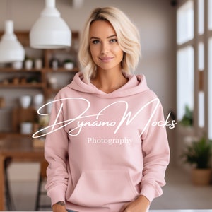 K&ouml;nnte beinhalten: Eine Frau tr&auml;gt einen rosa Kapuzenpullover mit dem Text "Dynamo Mocks Photography" auf der Vorderseite.