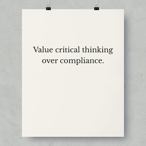Könnte beinhalten: Ein cremefarbenes Poster mit dem Text "Value critical thinking over compliance" in schwarzer Schrift. Das Poster wird von zwei schwarzen Büroklammern vor einem grauen Hintergrund gehalten.