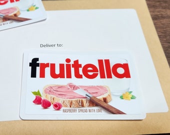 May include: A white card with the words "Deliver to:" and the Fruitella logo in red and black. The card features a photo of a slice of bread with pink raspberry spread and a knife. The text "Raspberry Spread with Love" is below the photo.
