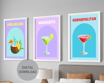 Puede incluir: Tres impresiones de arte de pared imprimibles con ilustraciones de cócteles. Las impresiones están en marcos blancos con un fondo azul claro, morado claro y azul claro. El texto en las impresiones dice "Piña Colada", "Margarita" y "Cosmopolitan".