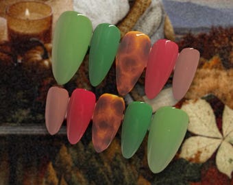 Peut inclure: Ensemble de dix faux ongles de différentes couleurs automnales, notamment vert, marron, rouge et nude. Les ongles sont en forme d'amande et ont une finition brillante.
