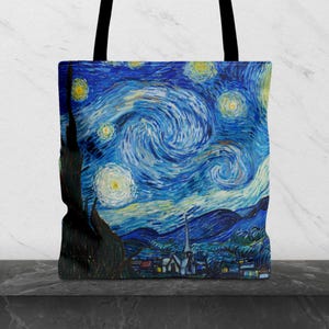 Op de afbeelding: Tote bag met een print van Van Gogh's "Starry Night". De tas toont de beroemde wervelende blauwe en gele nachthemel, met een dorpje aan de onderkant. Hij heeft zwarte handvatten en is gemaakt van een duurzame stof.