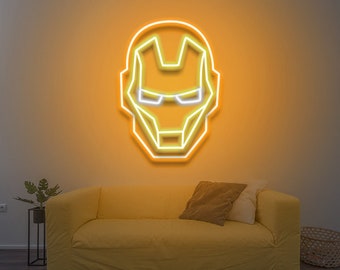 May include: A yellow neon sign shaped like Iron Man's face, with a white outline, is mounted on a wall above a yellow sofa.