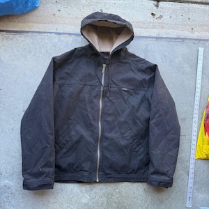 May include: A black hooded jacket with a beige fleece lining, a full-length brass-coloured metal zip, and two front pockets. A white ruler is positioned to the right, showing the jacket length is approximately 71 cm from top to bottom.